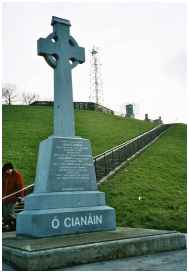 O' Cianain memorial; Derry walls and police observation tower behind.